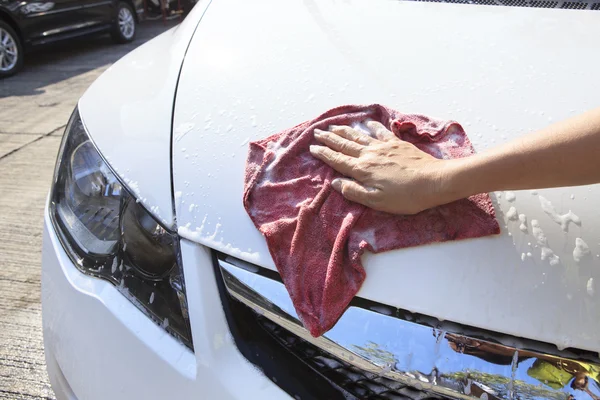 Hand with soft clothes washing passenger car at home