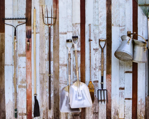 Farm tool pitchfork and two shovels against old wooden wall use