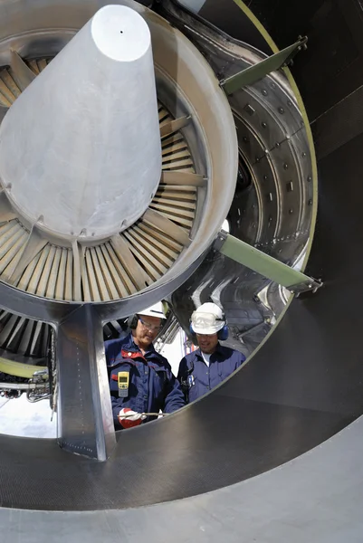 Airplane mechanics servicing a jet engine