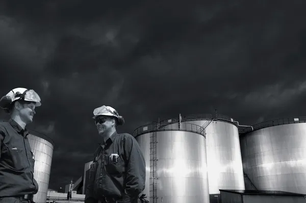 Refinery workers with fuel storage tanks