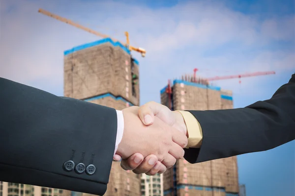 Businessman handshake with building construction background