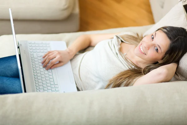 Young woman relaxing on the sofa with her laptop