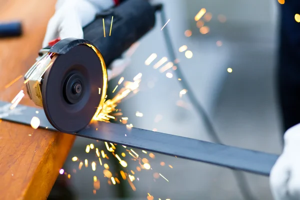 Worker using a grinder on a metal plate