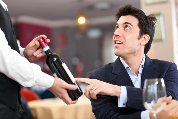 Waiter suggesting a bottle of wine to a customer