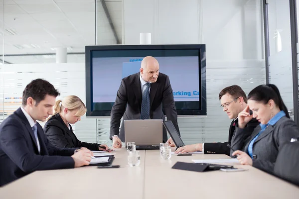 Angry boss at the meeting. Employess are looking down, afraid to