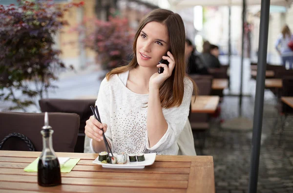 Beautiful young woman talking on the phone in a sushi restaurant