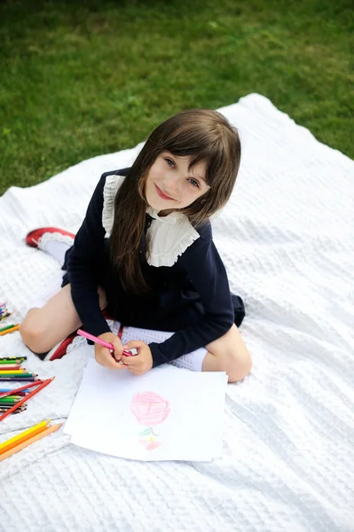Cute schoolgirl in navy uniform drawing a picture
