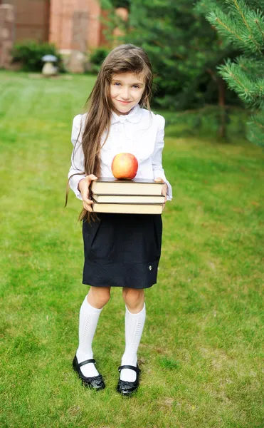 Young girl in school uniform with stack of books