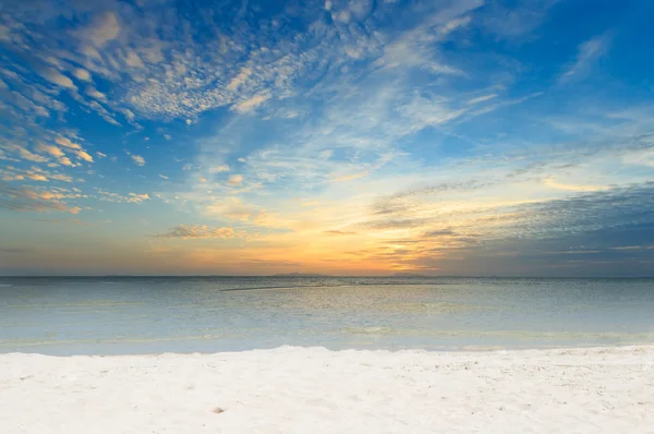 Dramatic sky sea and white sand beach at dawn