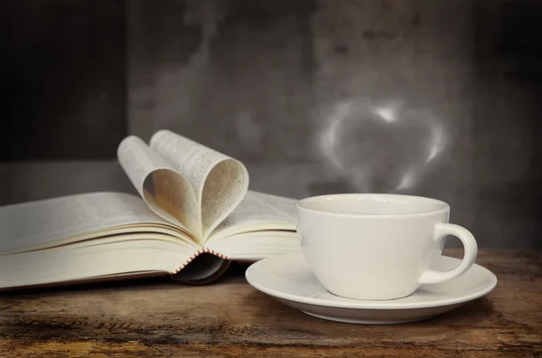 Still life with cup of coffee and book on grunge wood table in vintage style