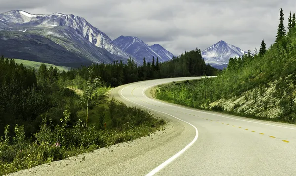 Asphalt road in high mountains of Alaska