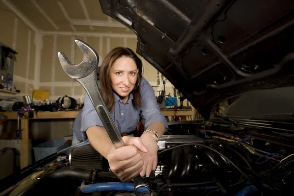 Hispanic woman in garage with wrench