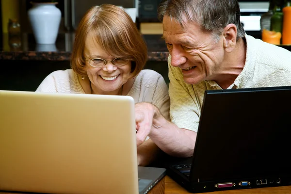 Senior couple using laptop computers at home
