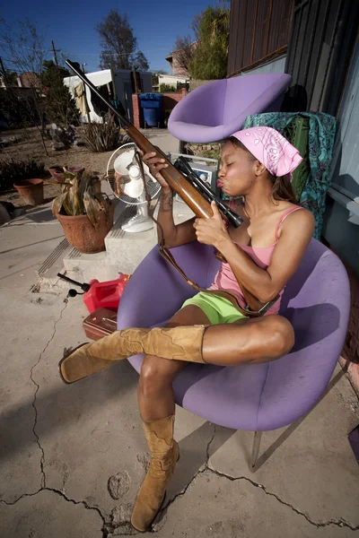 Black woman on back patio kissing rifle