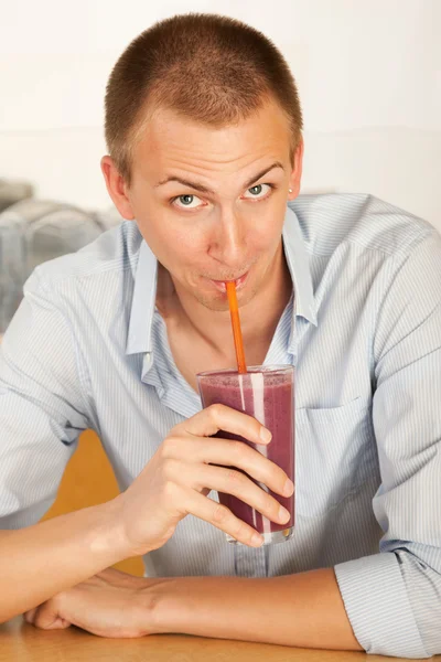 A young man drinking a frozen beverage