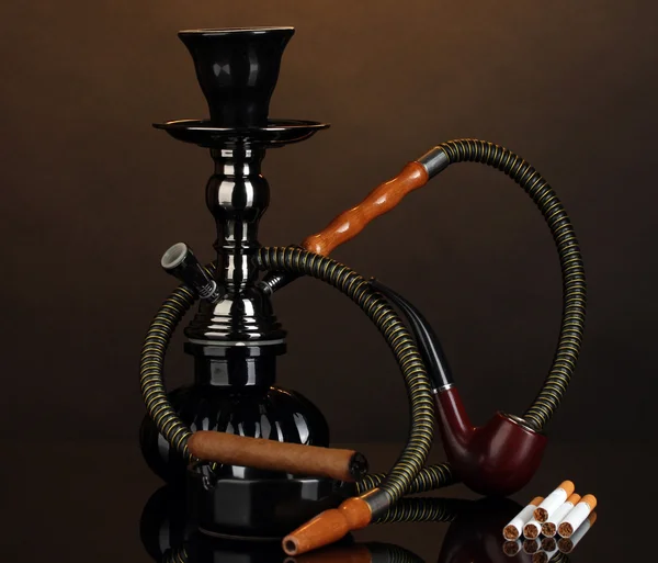 Smoking tools - a hookah, cigar, cigarette and pipe on brown background