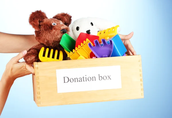 Donation box with children toys on blue background close-up