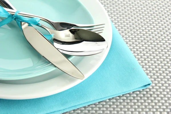 Blue empty plates with fork, spoon and knife on a grey tablecloth
