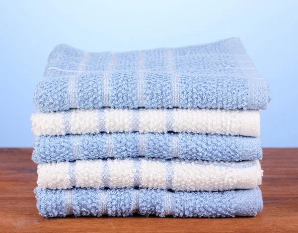 Kitchen towels on wooden table on blue background close-up