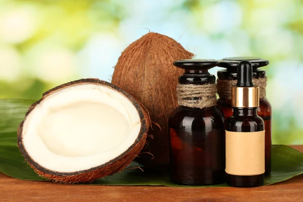 Coconut oil in bottles with coconuts on green background