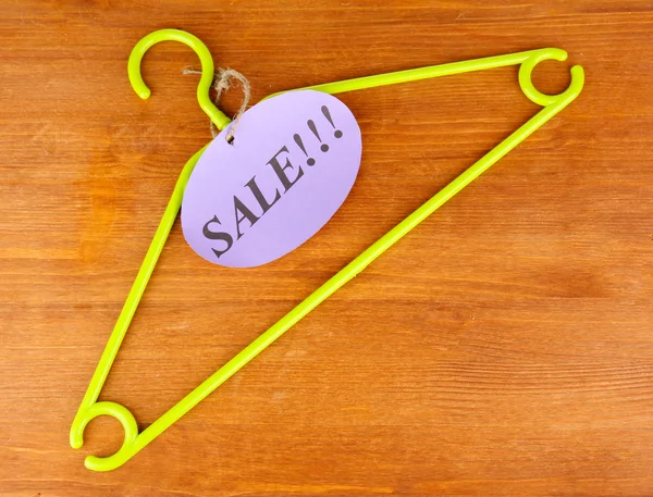 Coat hanger with sale tag on wooden background — Stock Photo #12713088