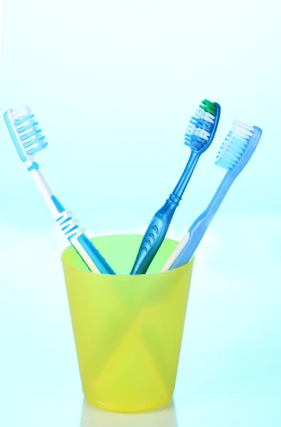 Toothbrushes in glass on blue background