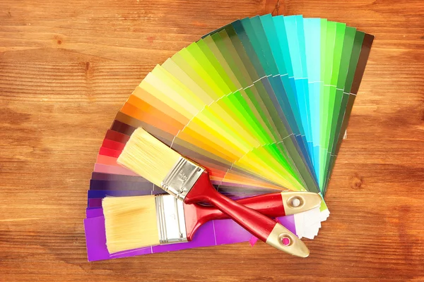 Paint brushes and bright palette of colors on wooden background