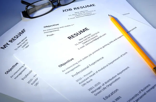 Closeup of resume with glasses and pencil on blue background