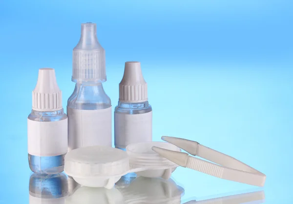 Eye drops and lenses on blue background