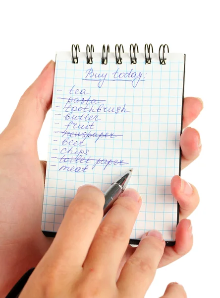 Woman\'s hand holding a notebook with a shopping list close-up