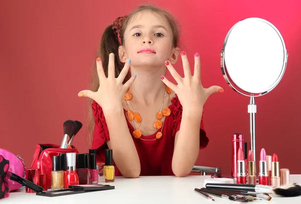 Little girl in her mother\'s dress, is trying painting her nails
