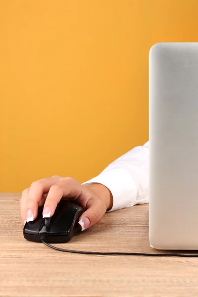 Woman's hands pushing keys of pc mouse, on yellow background close-up