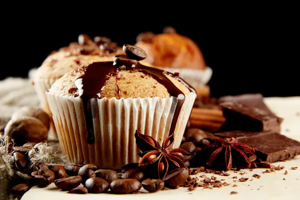 Tasty muffin cakes with chocolate, spices and coffee seeds, close up