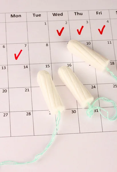 Menstruation calendar with cotton tampons, close-up
