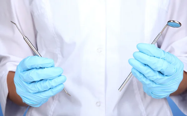 A dentists hands in blue medical gloves with dental tools