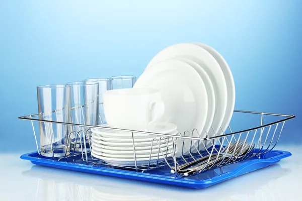Clean dishes on stand on blue background
