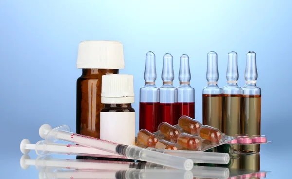 Medical ampules, bottles, pills and syringes on blue background