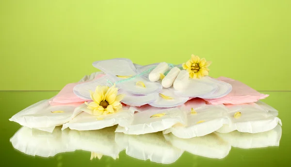 Various types of sanitary pads and tampons on green background close-up