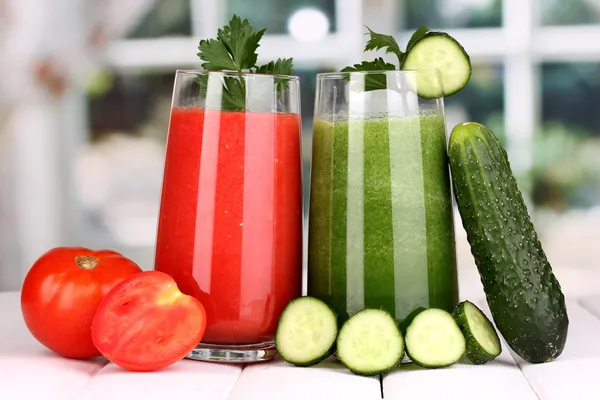 Fresh vegetable juices on wooden table, on window background