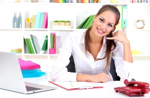 Young pretty business woman with phone and notebook working at office. Contact us