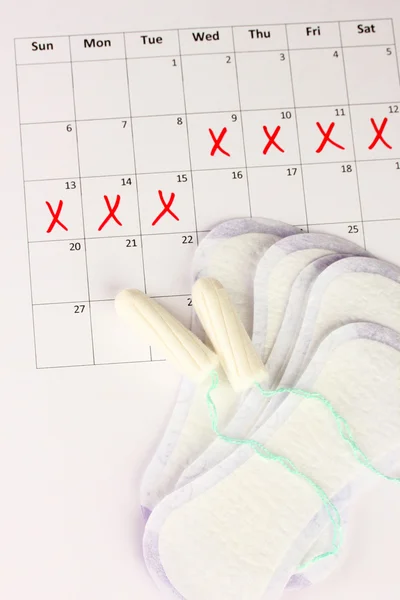 Menstruation calendar with sanitary pads and tampons, close-up