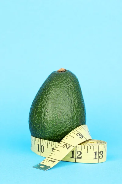 Avocado with measuring tape on blue background