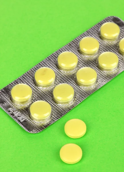 Pills packed in blister on green background
