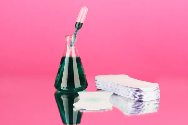 Testing sanitary pads for absorbency, on pink background close-up