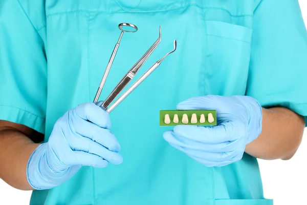 Dentists hands in blue medical gloves with dental tools and denture