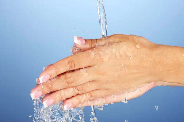 Washing woman\'s hands on blue background close-up