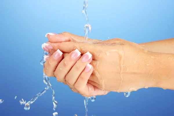 Washing woman\'s hands on blue background close-up