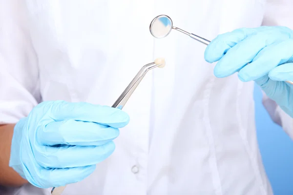 A dentists hands in blue medical gloves with dental tools