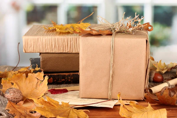 Autumnal composition with gift, books and leaves on bright background