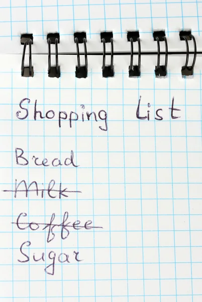 Shopping list in a notebook on white background close-up